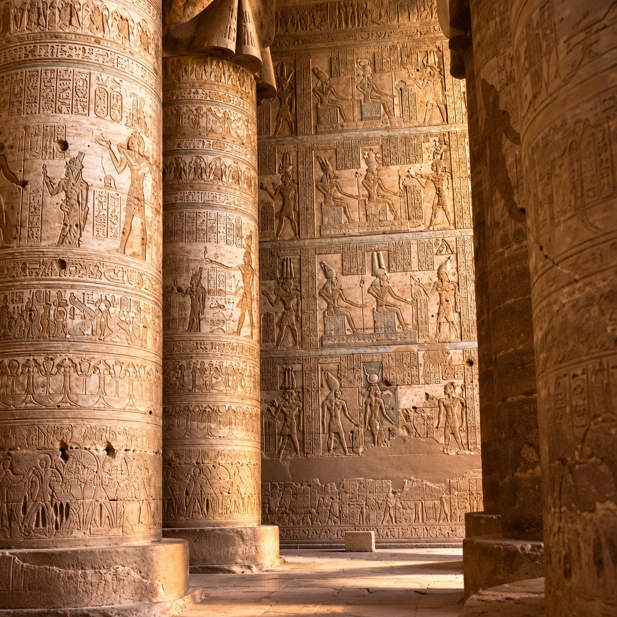 Intricately carved columns and walls covered with ancient Egyptian hieroglyphs at Abydos Temple.