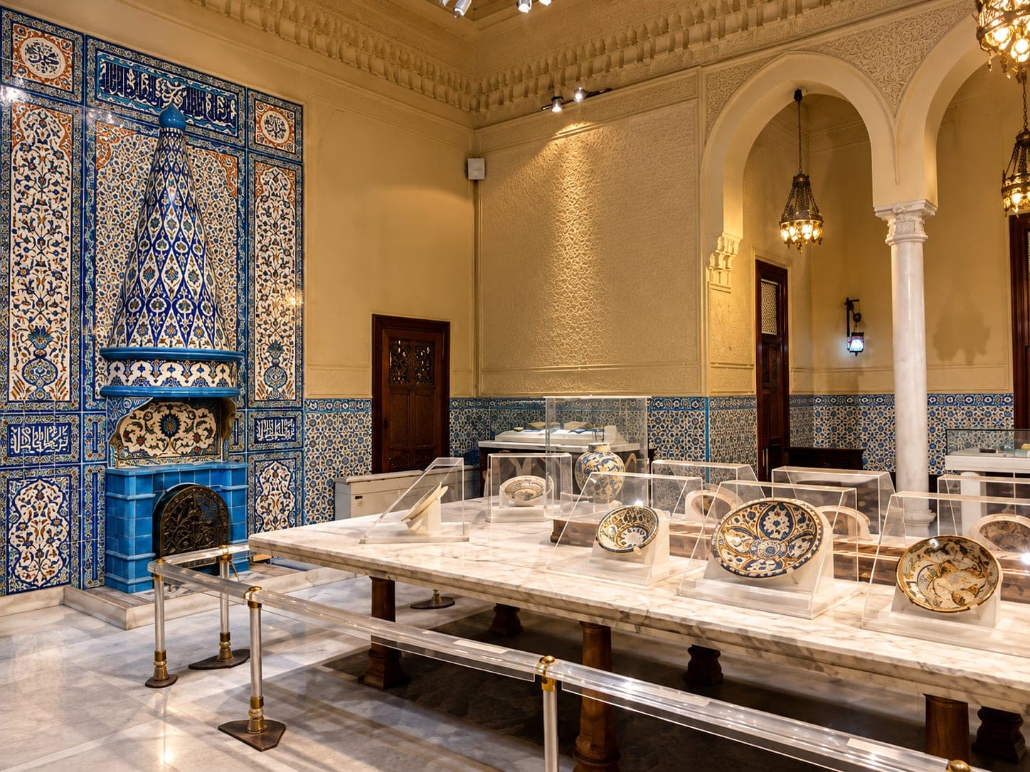 A beautifully decorated exhibition hall at the Museum of Islamic Art in Cairo, displaying Islamic ceramics, intricate blue tiles, and traditional architectural details.