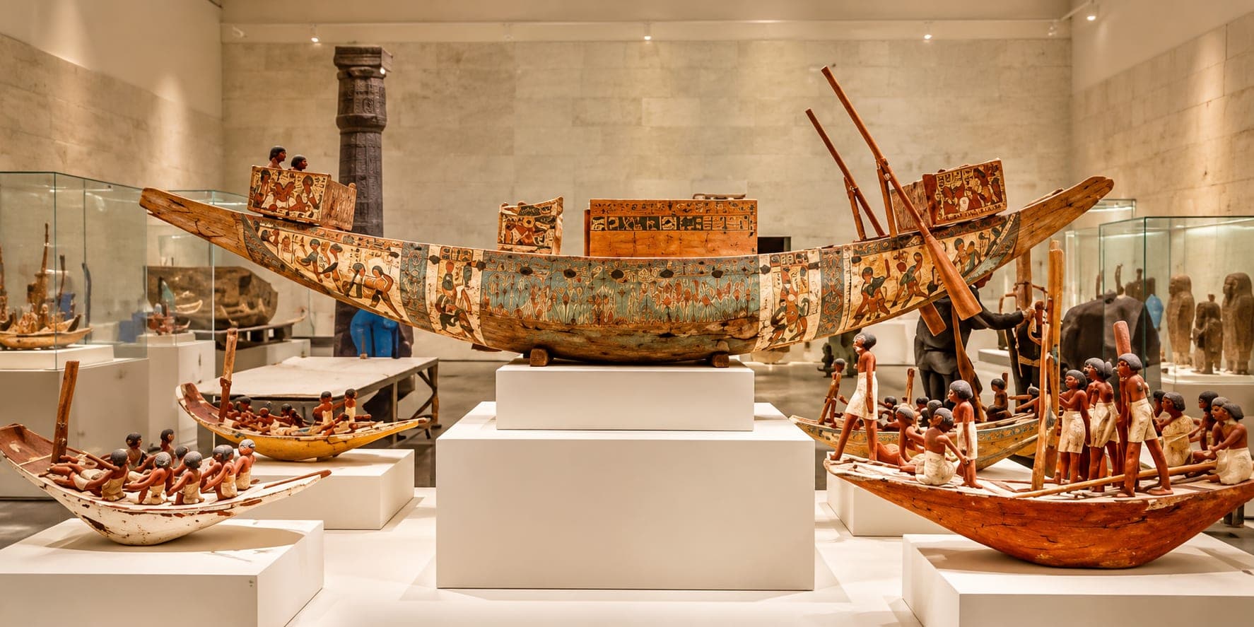 Ancient Egyptian wooden boat displayed inside the National Museum of Egyptian Civilization in Cairo, surrounded by historical artifacts.