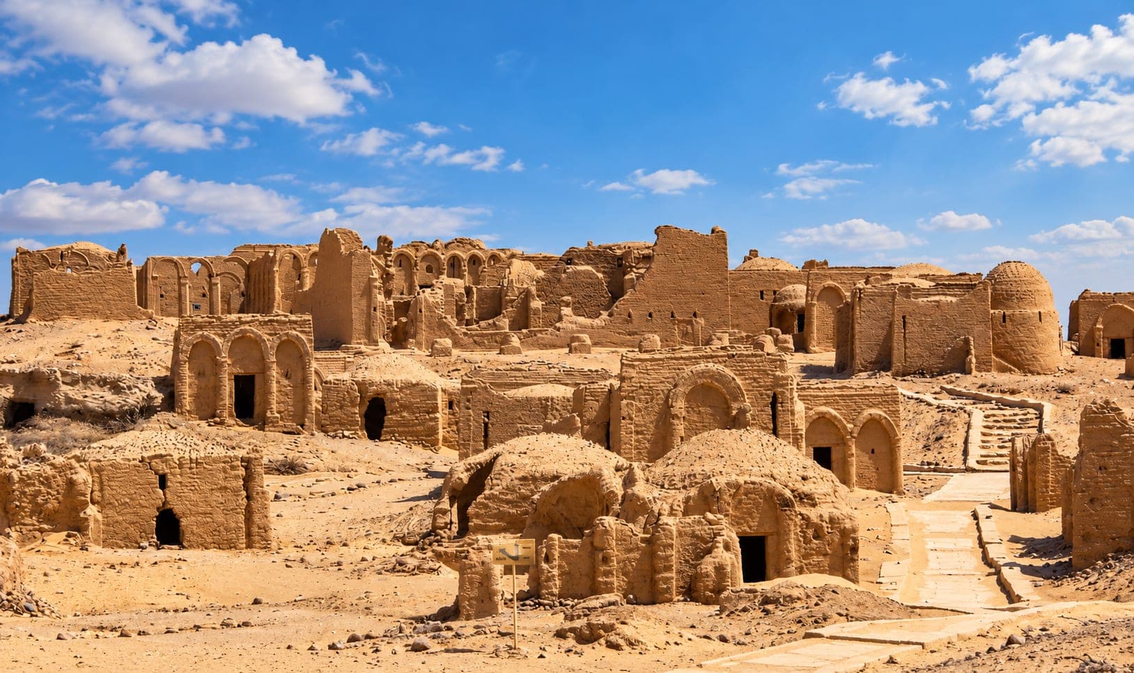 Historic mudbrick ruins in Kharga Oasis, Egypt, showing traditional desert architecture, arched doorways, and ancient buildings.